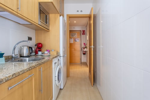 Modern kitchen in Alfa Living apartment at Haus Holiday Homes, San Pedro del Pinatar, featuring wooden cabinets, granite