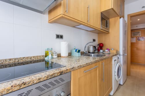 Modern kitchen with wooden cabinets, granite countertop, and appliances in Alfa Living apartment at Haus Holiday Homes, San
