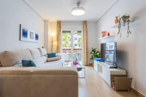 Bright modern living room with cream sofa, TV, and balcony access at Haus Holiday Homes, San Pedro del Pinatar