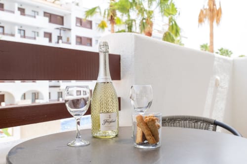 Sparkling wine bottle and glasses on a balcony table at Haus Holiday Homes in San Pedro del Pinatar, with crackers and city