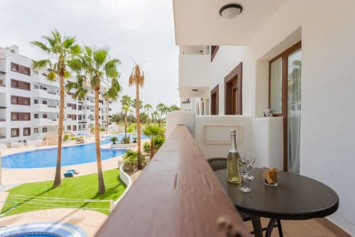 Balcony at Haus Holiday Homes in San Pedro del Pinatar with pool and palm tree views, champagne bottle on table
