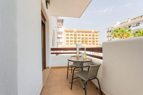 Sunny balcony at Haus Holiday Homes in San Pedro del Pinatar with dining table, chair, and resort pool view