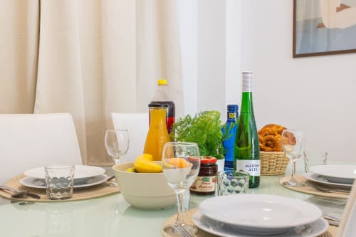 Elegantly set dining table at Haus Holiday Homes in San Pedro del Pinatar with white plates, wine glasses, fresh fruits, and