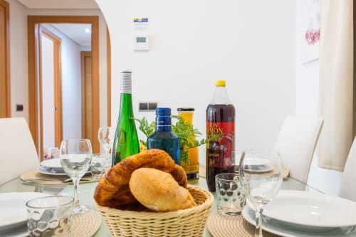 Dining table set with bread basket, wine bottles, and glassware at Haus Holiday Homes apartment in San Pedro del Pinatar,