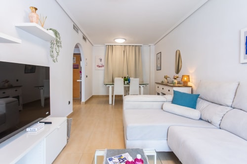 Bright apartment living room at Haus Holiday Homes in San Pedro del Pinatar with white sofa, TV, kitchen, and modern