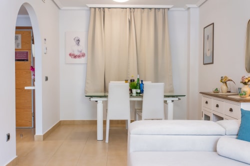 Modern apartment living area at Haus Holiday Homes with dining table, white sofa, and kitchenette in San Pedro del Pinatar