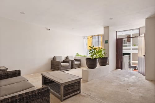 Modern oceanview apartment lounge at Malkita Sol, Isla Mujeres with wicker seating, potted plants, and sea-view doors