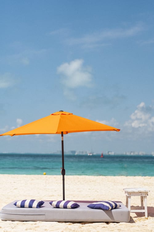 Orange beach umbrella with striped loungers overlooking turquoise ocean at Malkita Homes, Isla Mujeres