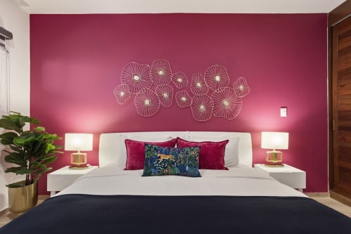 Modern bedroom at Malkita Sol in Isla Mujeres with vibrant pink accent wall, white bed, decorative wall art, and side lamps
