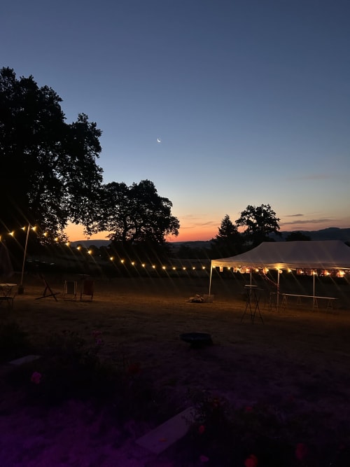 Installation de glamping en soirée au Château de Vaux Morvan avec tentes illuminées et croissant de lune au crépuscule
