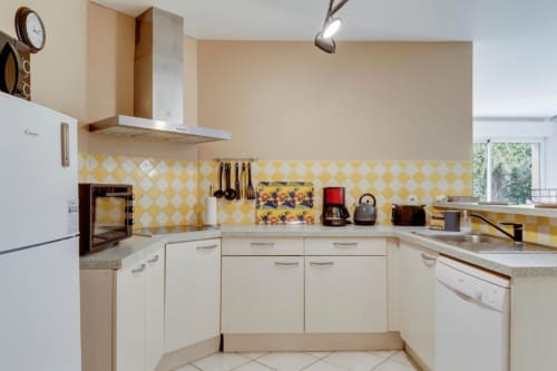 Cuisine jaune éclatant aux motifs géométriques de la maison d'hôtes Les Petits Toits à Libourne, armoires blanches et électroménagers modernes