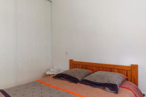 Chambre douillette du gîte Les Petits Toits à Libourne avec lit en bois, coussins à motifs et vue sur le jardin
