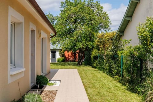 Vue du jardin cottage des Petits Toits à Libourne avec terrasse, pelouse et arbres matures