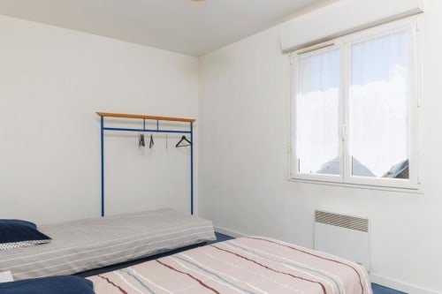 Chambre lumineuse du gîte Les Petits Toits à Libourne avec deux lits, portant bleu et vue sur le jardin