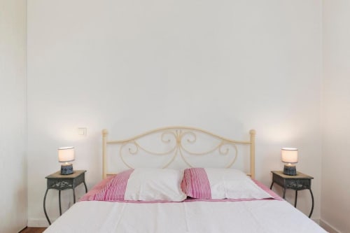 Chambre élégante de la maison d'hôtes Les Petits Toits à Libourne avec tête de lit ornementée, oreillers rose rayé et lampes de chevet