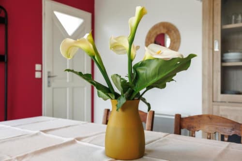 Lys calla jaunes dans un vase doré sur la table à manger du gîte Les Petits Toits, Libourne