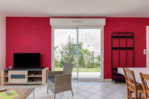 Lumineux séjour aux murs rouges avec TV, portes sur jardin et coin repas aux Petits Toits, Libourne