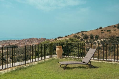 Patio della Sala dell'Ulivo al Baglio Capo di Siculiana, Sicilia, con poltrona relax affacciata su giardino e vista costiera