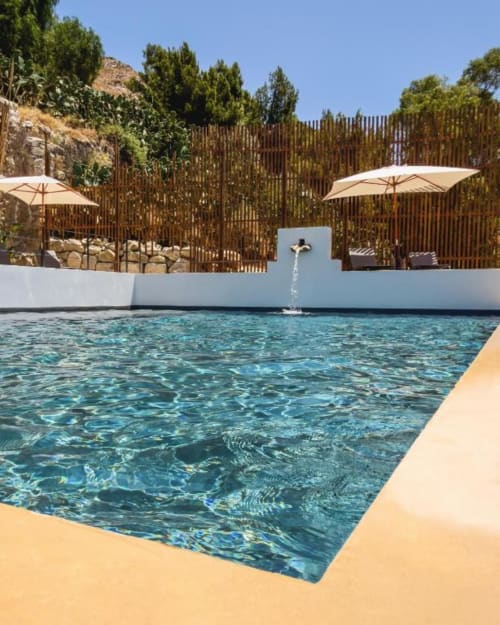 Piscina cristallina alla villa Baglio Capo di Siculiana con ombrelloni bianchi, schermi in legno e fontana a croce