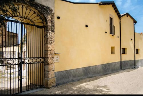 Ingresso della villa Baglio Capo a Siculiana con muri gialli, cancellata in ferro decorativo e arco in pietra