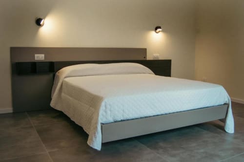 Camera moderna della villa Baglio Capo con letto queen, testata scura, biancheria bianca e illuminazione ambientale a Siculiana, Sicilia