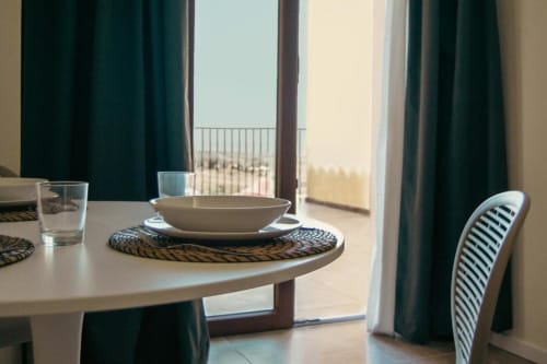 Sala da pranzo della Suite Gelsomino a Baglio Capo con terrazza con vista sul lago, tavolo apparecchiato e tendaggi turchesi