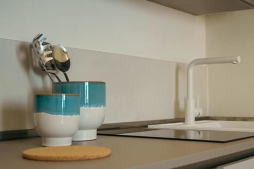 Cucinetta moderna nella Suite Rosmarino del Baglio Capo con contenitori in ceramica turchese, rubinetto bianco e design minimalista