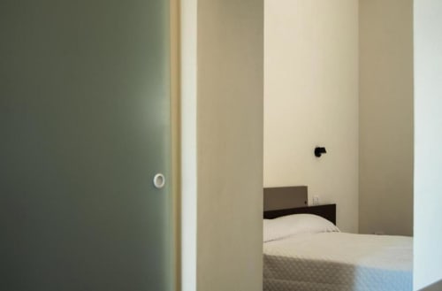 Veduta dalla porta della camera Gelsomino al Baglio Capo, Siculiana, con letto e arredamento neutro