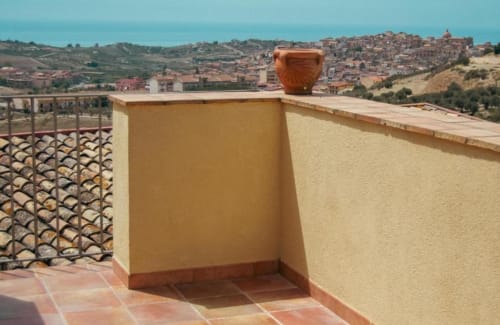 Terrazza della Rosmarino Suite a Baglio Capo con vaso in terracotta che domina il borgo collinare di Siculiana, Sicilia