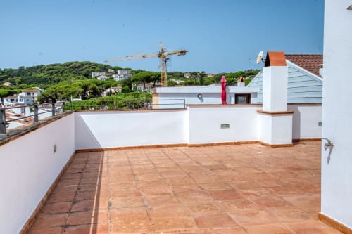 Rooftop terrace with terracotta tiles, white walls, and views of Calella de Palafrugell hillside homes and green landscape