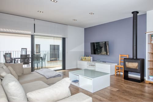 Modern duplex apartment living room in Calella with cream sofa, fireplace, flat-screen TV, and terrace access