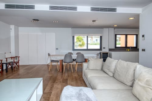 Modern duplex apartment living area in Calella with dining table, kitchen, sofa, and hardwood floors