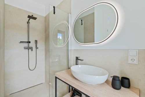 Modern bathroom in Mattbnb Metz with round LED mirror, white vessel sink, and walk-in shower with black fixtures