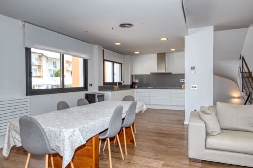 Modern duplex apartment in Calella with open-plan dining, kitchen, and living area featuring wooden floors and contemporary