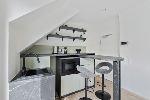 Modern kitchenette with black marble countertops, bar seating, and open shelving in Mattbnb Metz room