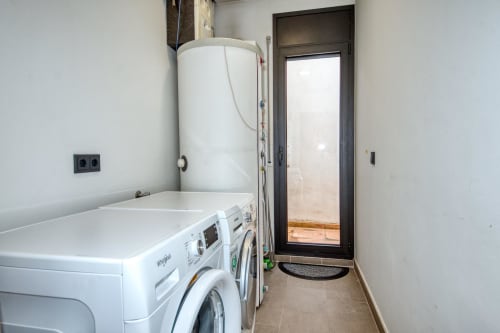 Laundry room in Calella duplex apartment with washing machines, dryer, and water heater