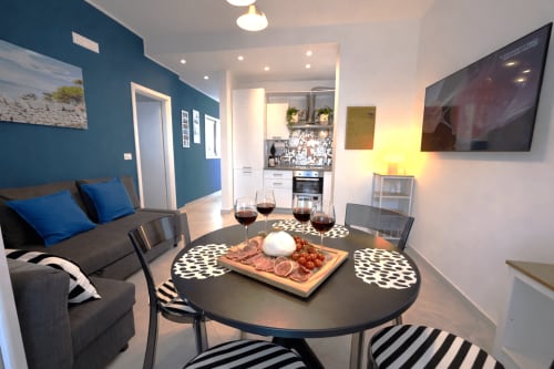 Zona pranzo dell'appartamento moderno a Bari con tavolo rotondo nero, coperto e cucina a vista presso Appartamenti Bari