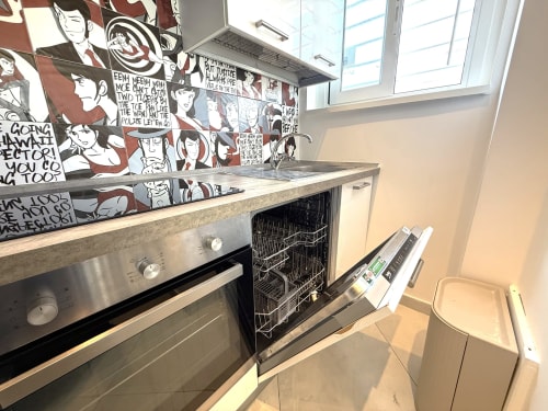 Cucina moderna nell'appartamento Terrazza Visconti a Bari, con elettrodomestici in acciaio inox e rivestimento a tema anime