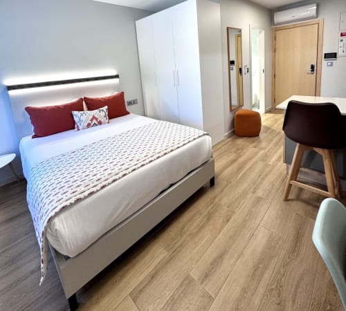 Chambre moderne au RIA CENTRUM Smart Residence à Aveiro avec lit queen-size, oreillers rouges, parquet et armoire blanche