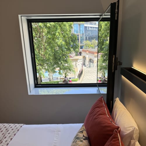 Fenêtre de chambre d'hôtel moderne surplombant la place d'Aveiro avec arbres et architecture historique au RIA CENTRUM Smart Residence