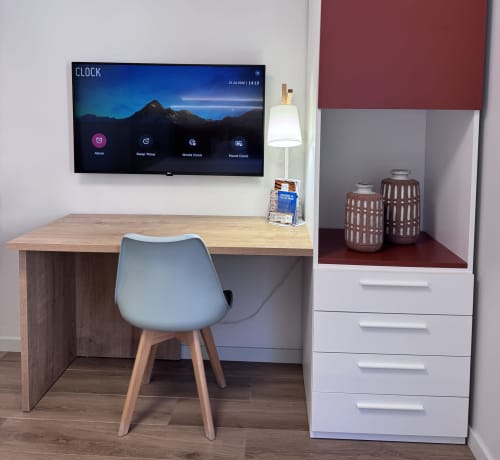 Espace de travail moderne au RIA CENTRUM Smart Residence à Aveiro avec bureau, chaise, TV murale affichant l'application horloge
