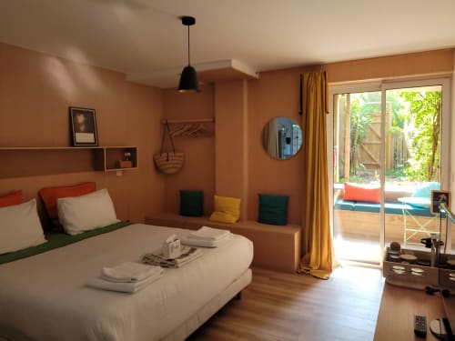 Camera moderna al Lodge du Cap Ferret con pareti color terracotta, letto bianco e vista sul giardino privato attraverso porte vetrate