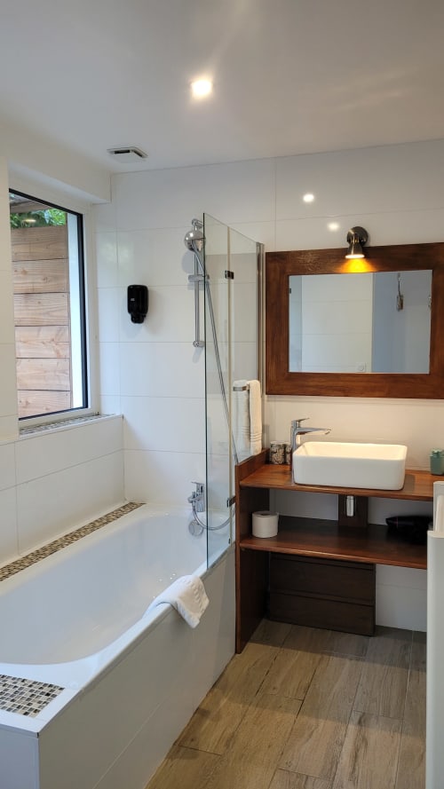 Bagno moderno presso Le Lodge du Cap Ferret con doccia a filo pavimento, vasca indipendente, mobile bagno in legno e finestra con vista giardino