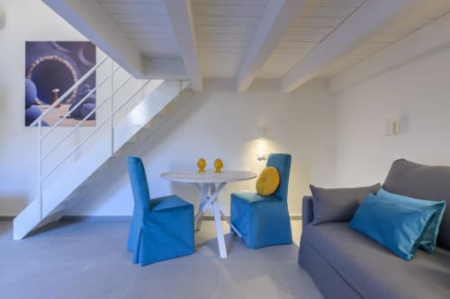 Appartamento Blu Ottanio all'hotel Almatros di Sulmona con sedie blu, tavolo da pranzo bianco e zona living moderna
