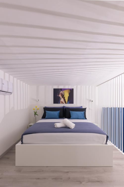 Camera moderna dell'Almatros Sulmona con letto dal design minimale contemporaneo, cornice bianca e biancheria blu