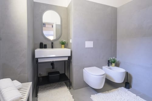 Moderno bagno dell'hotel Almatros a Sulmona con wc, bidet, specchio ovale e mobile lavabo nero