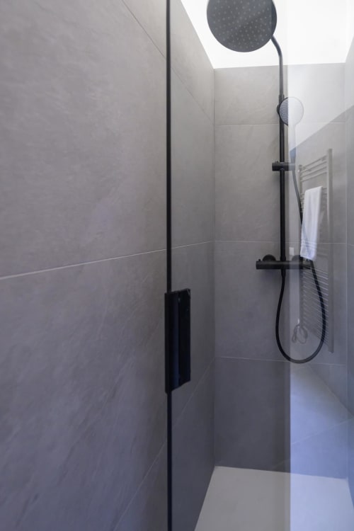 Moderna doccia nell'appartamento Blu Ottanio dell'hotel Almatros a Sulmona, con soffione a pioggia e rubinetteria nera