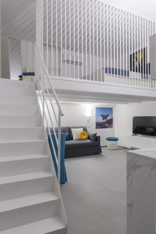 Appartamento Blu Ottanio ad Almatros Sulmona con loft, scale bianche, divano scuro e arredamento moderno