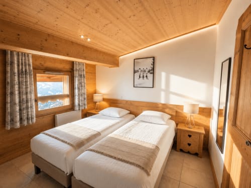 Lits jumeaux dans chambre de chalet alpin avec poutres apparentes, vue sur le Mont-Blanc et décoration montagnarde chez Cosyarc