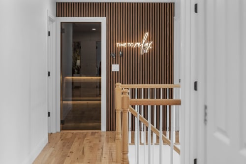 Modern entryway at Malkita Terra villa with wood slat accent wall, neon 'TIME TO RELAX' sign, and white staircase